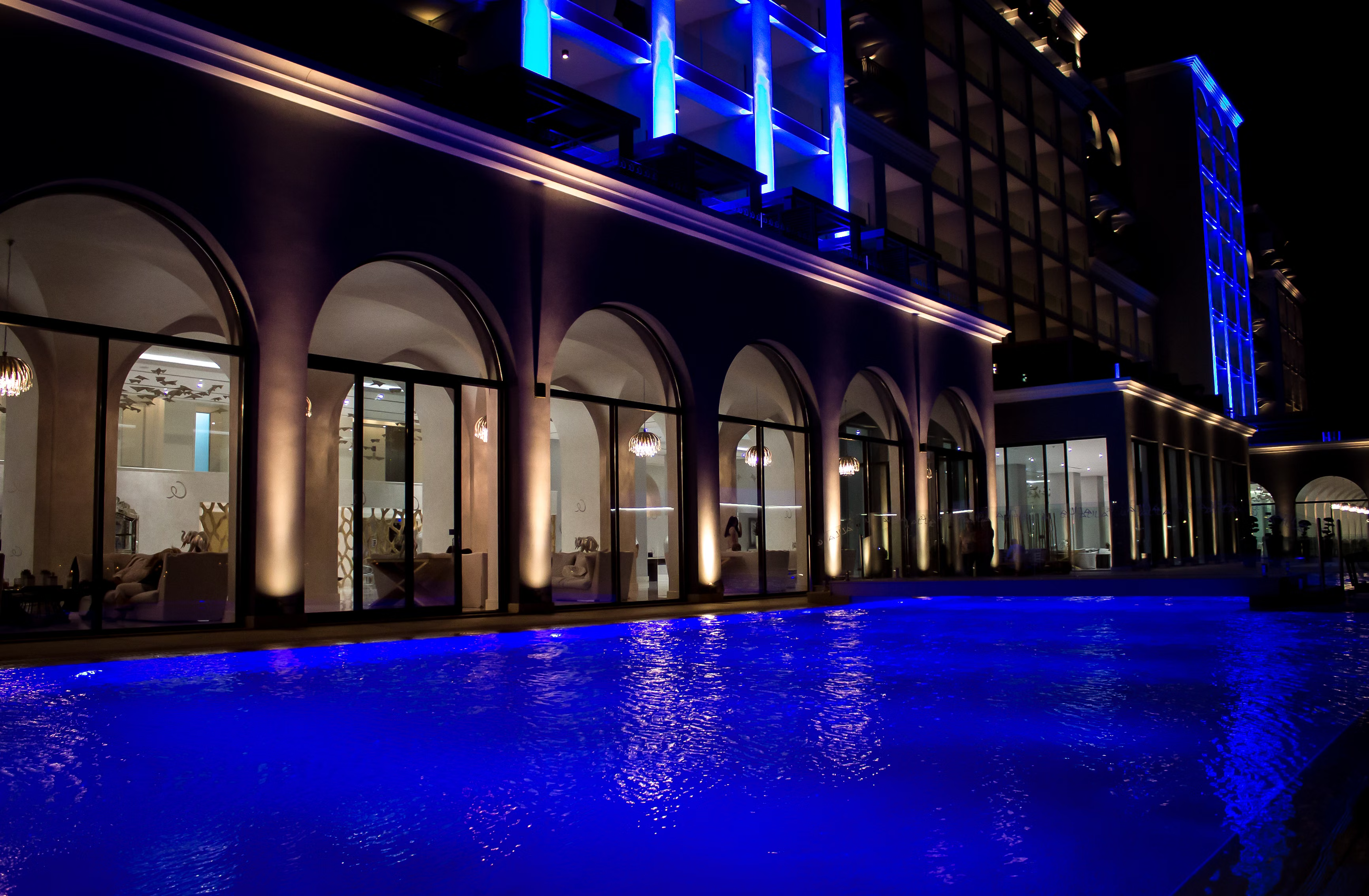 Illuminated building facade and pool at night